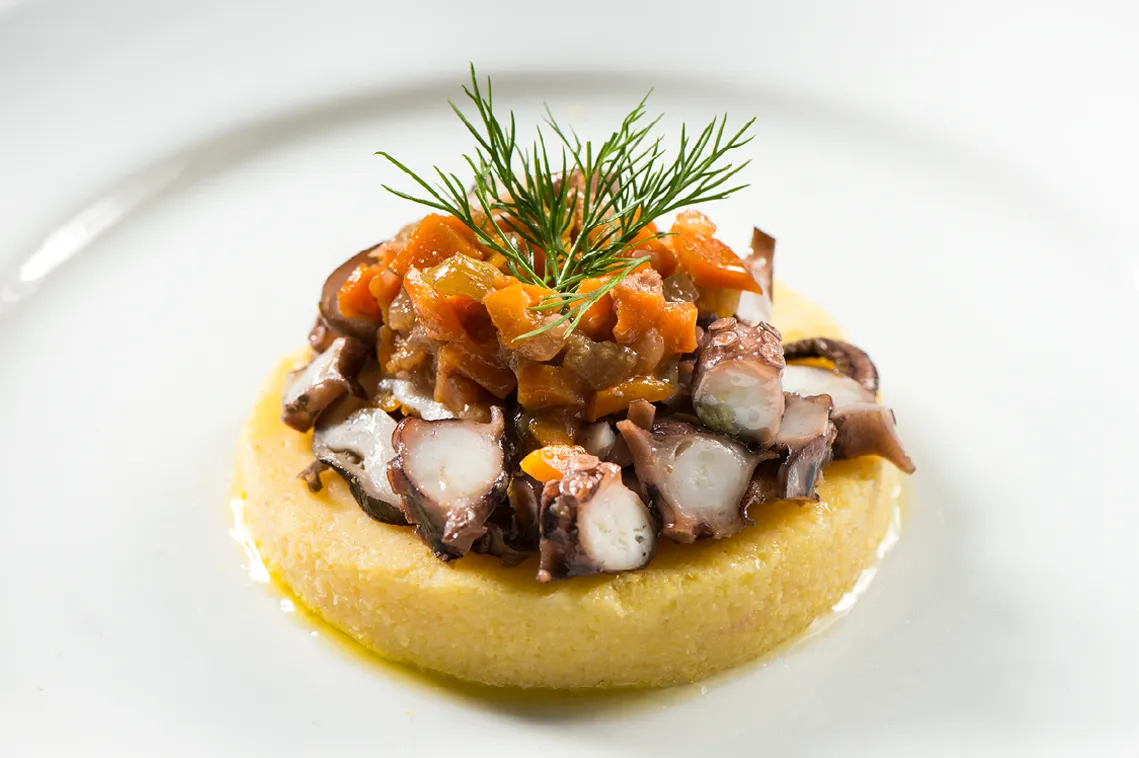 Portata di servizio catering per fiere con polpo su polenta